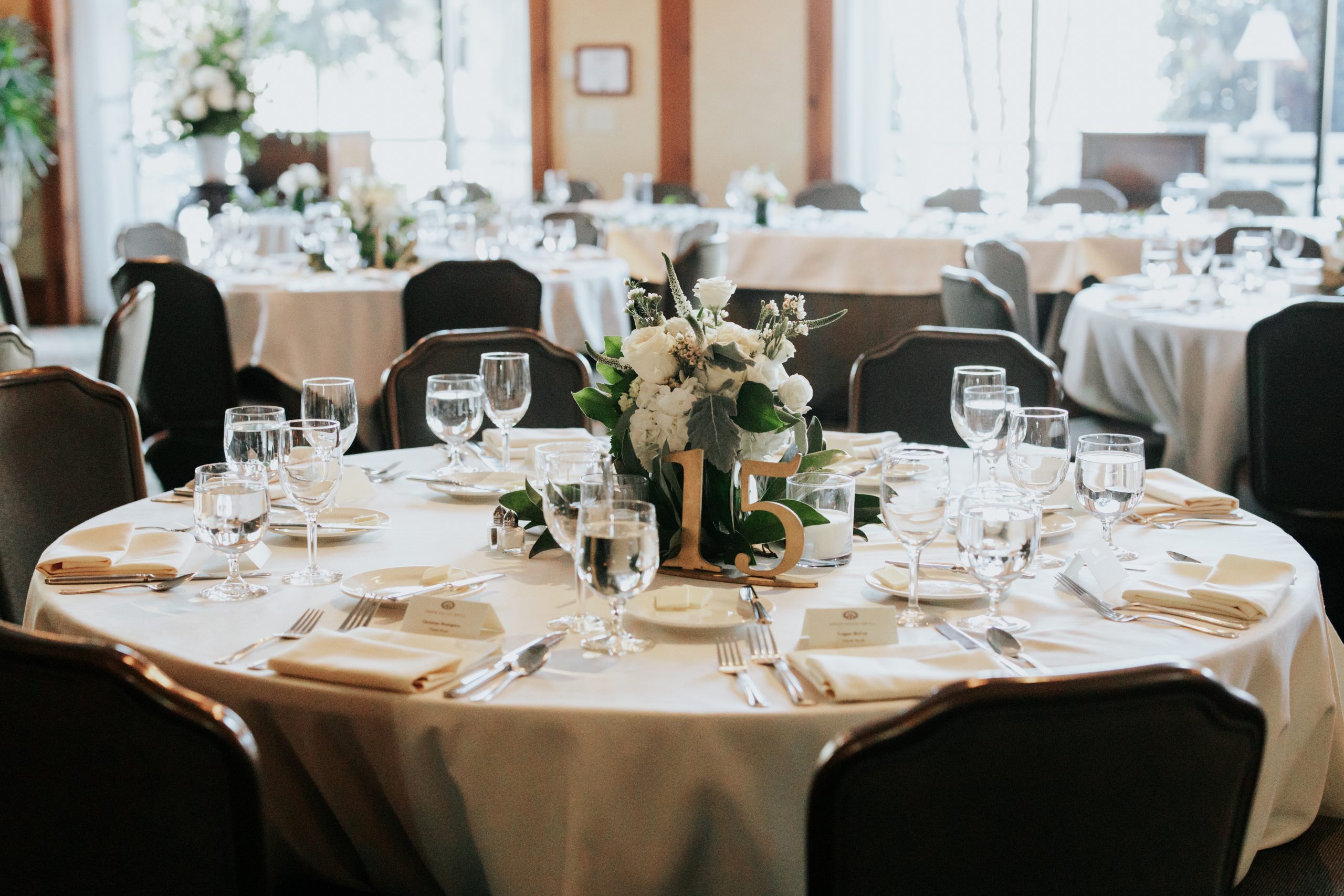 Caldwell Room with Rounds of 8 | The largest banquet space at O.Henry Hotel opens to the Social Lobby. The Caldwell Room features four outside arched windows and access to an intimate courtyard area. The room can accommodate larger receptions, up to 144 seated guests, and 175 at a standing reception. Named after a Greensboro forefather and esteemed educator, David Caldwell, it can divide into six different combinations.